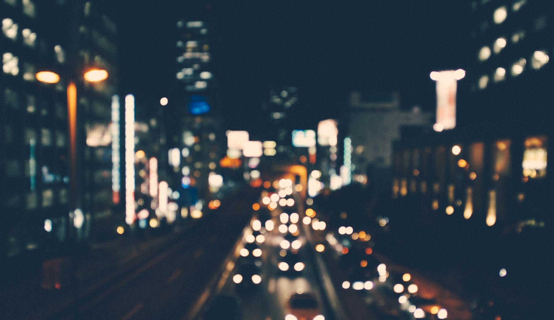 A blurry shot of a city street lit up by buildings and cars at night